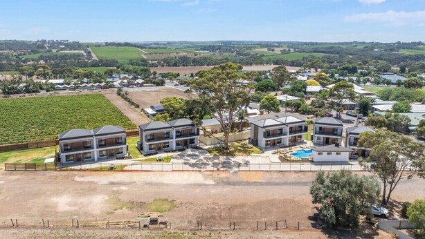 Zona residencial con casas modernas, una piscina y un viñedo al fondo.