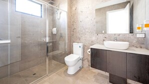 A modern bathroom with a glass-enclosed shower, a toilet, a sink, and a mirror above the vanity.