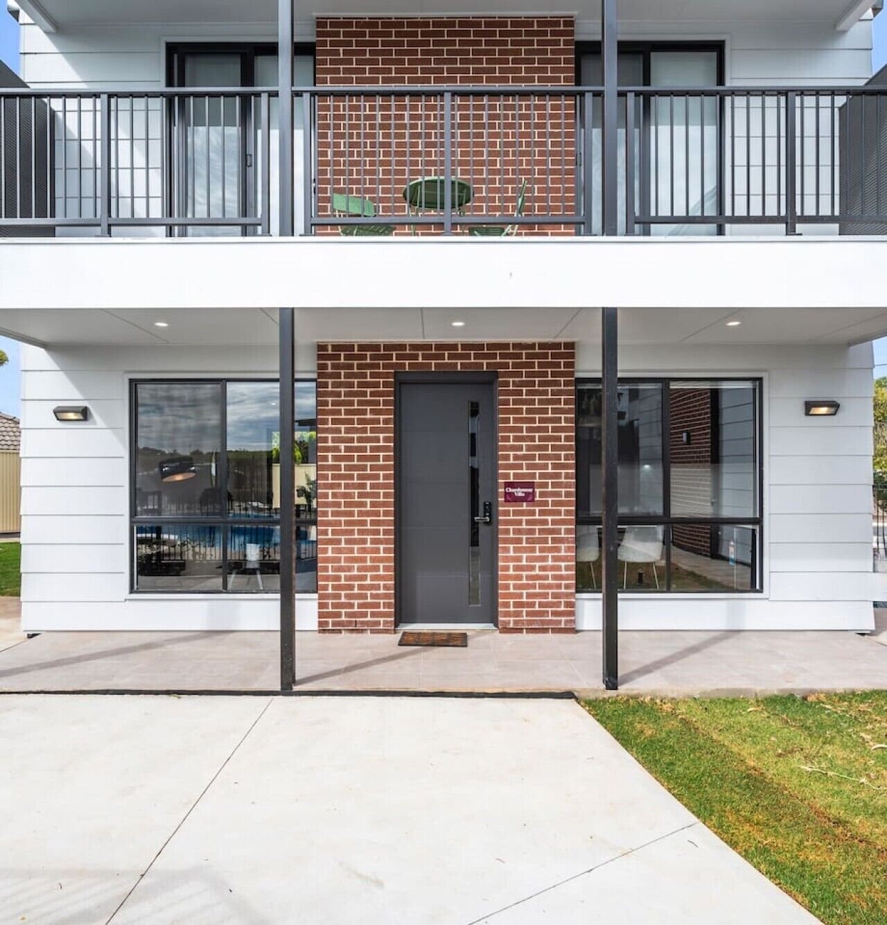 A two-story building with a brick facade, large windows, and a balcony with metal railings.