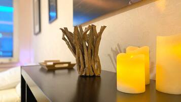A wooden branch decoration on a dark wooden table next to two lit candles.