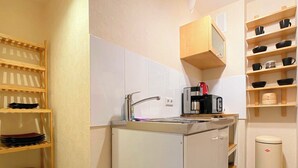 Une petite cuisine équipée d’un évier, d’une machine à café et d’une poubelle.