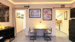 Une chambre d’hôtel équipée d’une table à manger, de deux chaises, d’un petit coin cuisine et d’un téléviseur.