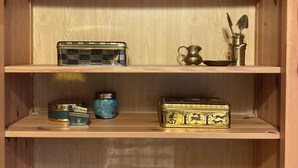Une étagère en bois ornée de divers objets décoratifs, notamment des figurines, une radio et une boîte en métal.