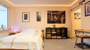 Une chambre à coucher comprenant un lit, des tables de chevet, un bureau et une étagère ornée d’objets décoratifs.