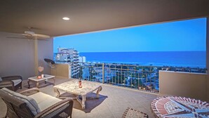 A balcony with a view of the sea and cityscape, furnished with wicker chairs and a table. - Condo Bella Sirena 805 C by Kivoya (Puerto Peñasco)