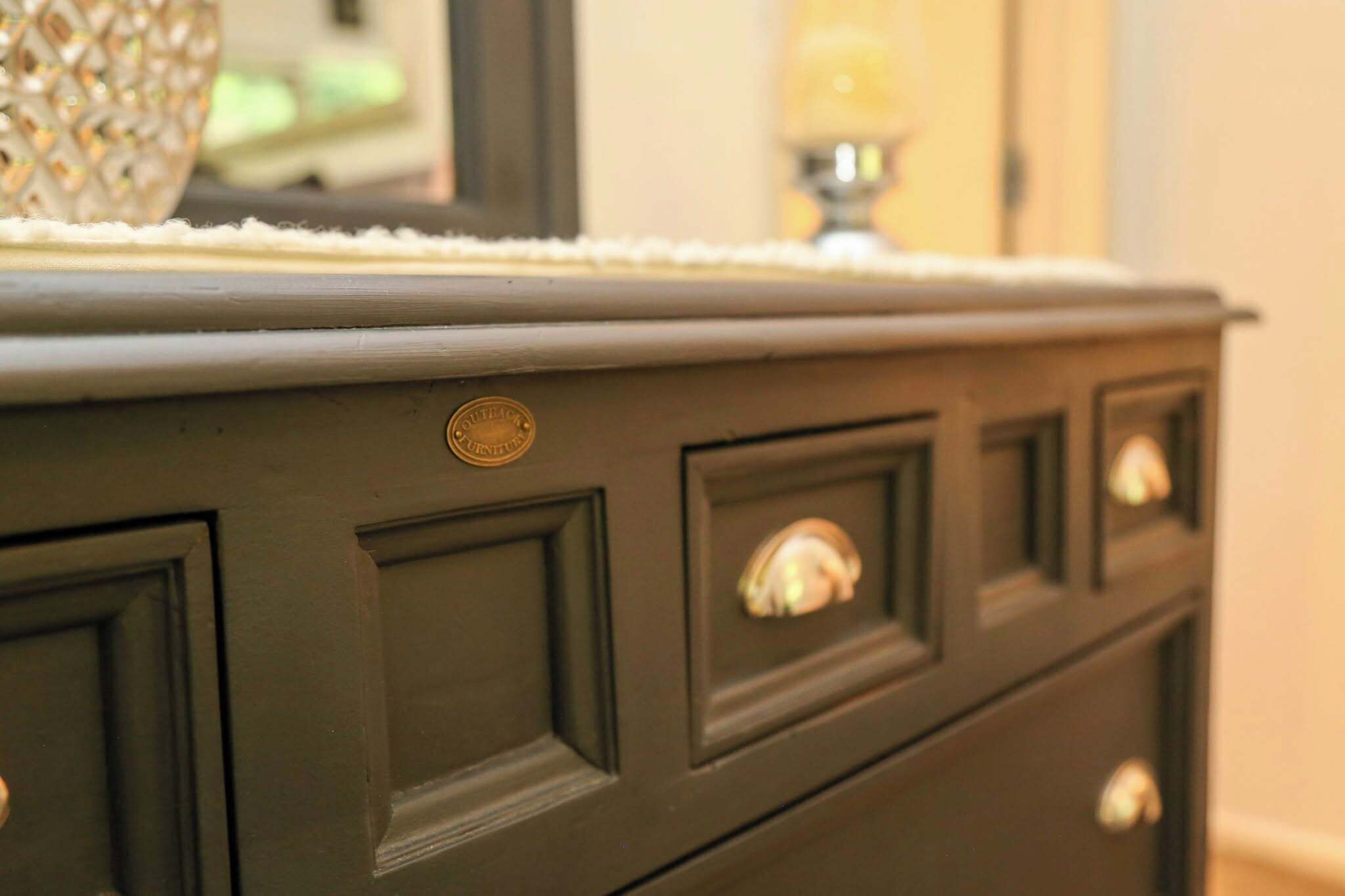 A dark wooden dresser with a mirror and a decorative item on top.