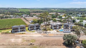 Un quartier résidentiel avec des maisons modernes, une piscine et, au loin, un vignoble.