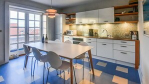 A modern kitchen with white cabinets, a dining table with chairs, and a patterned floor.