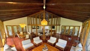 A spacious room with a high ceiling, wooden furniture, and large windows. - Spacious Gated Casa de Campo 5-bedroom Villa w/ Pool/Hot Tub and Hi speed WiFi (La Romana)