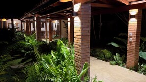 A covered outdoor area with brick pillars and a concrete pathway surrounded by lush green ferns. - Spacious Gated Casa de Campo 5-bedroom Villa w/ Pool/Hot Tub and Hi speed WiFi (La Romana)