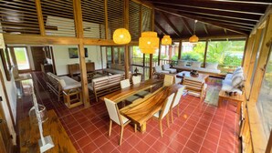 A spacious outdoor dining area with wooden furniture and a red tiled floor.