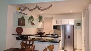 A modern kitchen with a central island, white cabinets, a stainless steel refrigerator, and hanging plants. - 2-bedroom resort in wonderful Playas del Coco with WiFi, AC; extra sleeper  (Playas del Coco)