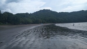 A beach with a sandy shore and a forested hill in the background. - 2-bedroom resort in wonderful Playas del Coco with WiFi, AC; extra sleeper  (Playas del Coco)