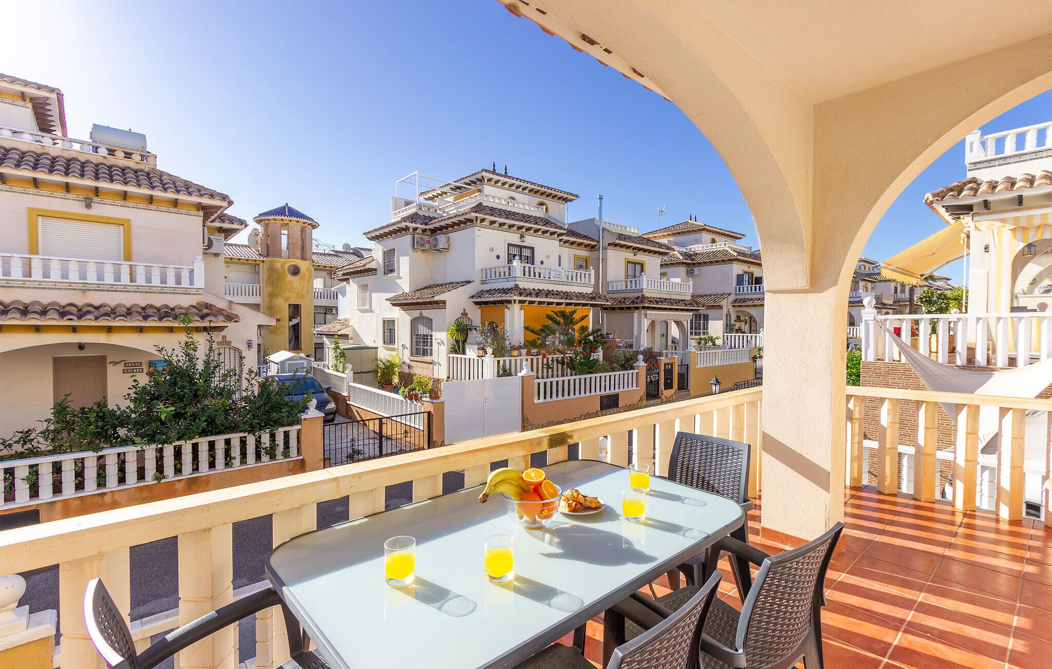A balcony with a table set for breakfast, overlooking a residential area with traditional architecture.