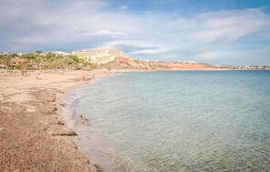 A beach with clear water, a sandy shore, and a large building in the background. - Beautiful home in Orihuela Costa (Orihuela Costa)