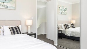 Une chambre d’hôtel avec un lit, des tables de chevet, un miroir et des œuvres d’art abstraites accrochées au mur.
