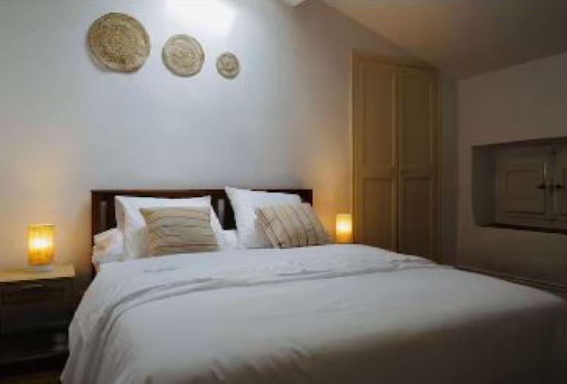 A bedroom with a bed, nightstands, and wall decor.