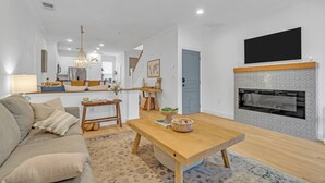 Un salon moderne avec une table basse en bois, un canapé, une cheminée et un ventilateur de plafond.