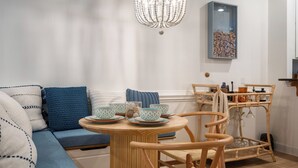 Un salon chaleureux avec un canapé bleu, une table en bois sur laquelle sont disposés des services à thé et un lustre décoratif.