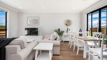 A modern living room with a sofa, TV, dining table, and chairs.