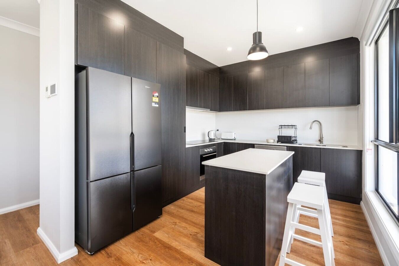 A modern kitchen with dark cabinetry, a central island, and a white countertop.