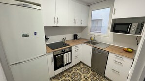 A compact kitchen with white cabinets, a microwave, a sink, and a stove.