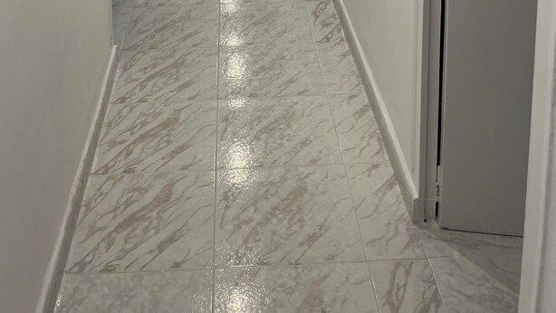 A hallway with white walls, a marble floor, and recessed lighting.