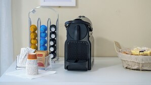 A coffee machine, a basket of snacks, and a container of napkins on a table. - Vitti's home Verona 5 (Verona)