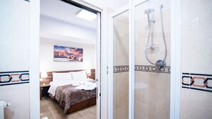 A hotel room with a bed, a nightstand, a shower with a glass door, and a painting on the wall. - Vitti's home Verona 5 (Verona)
