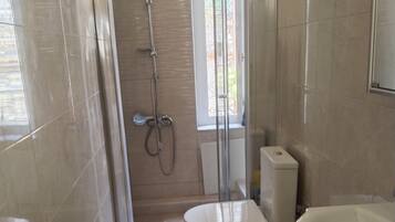 Un baño moderno con ducha de vidrio, inodoro y lavamanos.