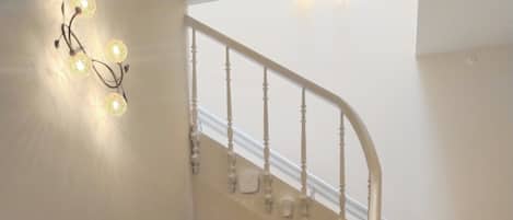 A staircase with a white railing, a dark wooden console table with a framed picture, and a white door at the bottom.