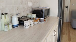 A kitchen with a toaster, a microwave, salt and pepper shakers, and a tray with bread and mugs. - 1920  classic (Kalamata)