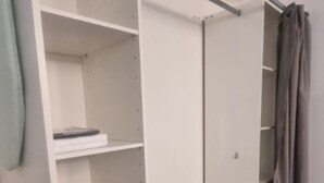 A walk-in closet with open shelving, a sliding door closet, and a grey curtain.
