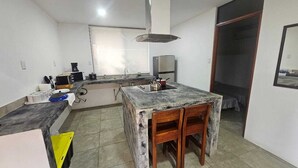 Una cocina compacta con encimera de mármol, sillas de madera, un lavabo y una estufa.