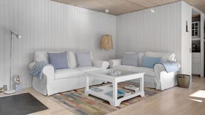 A modern living room with two white sofas, a glass coffee table, and a striped rug.
