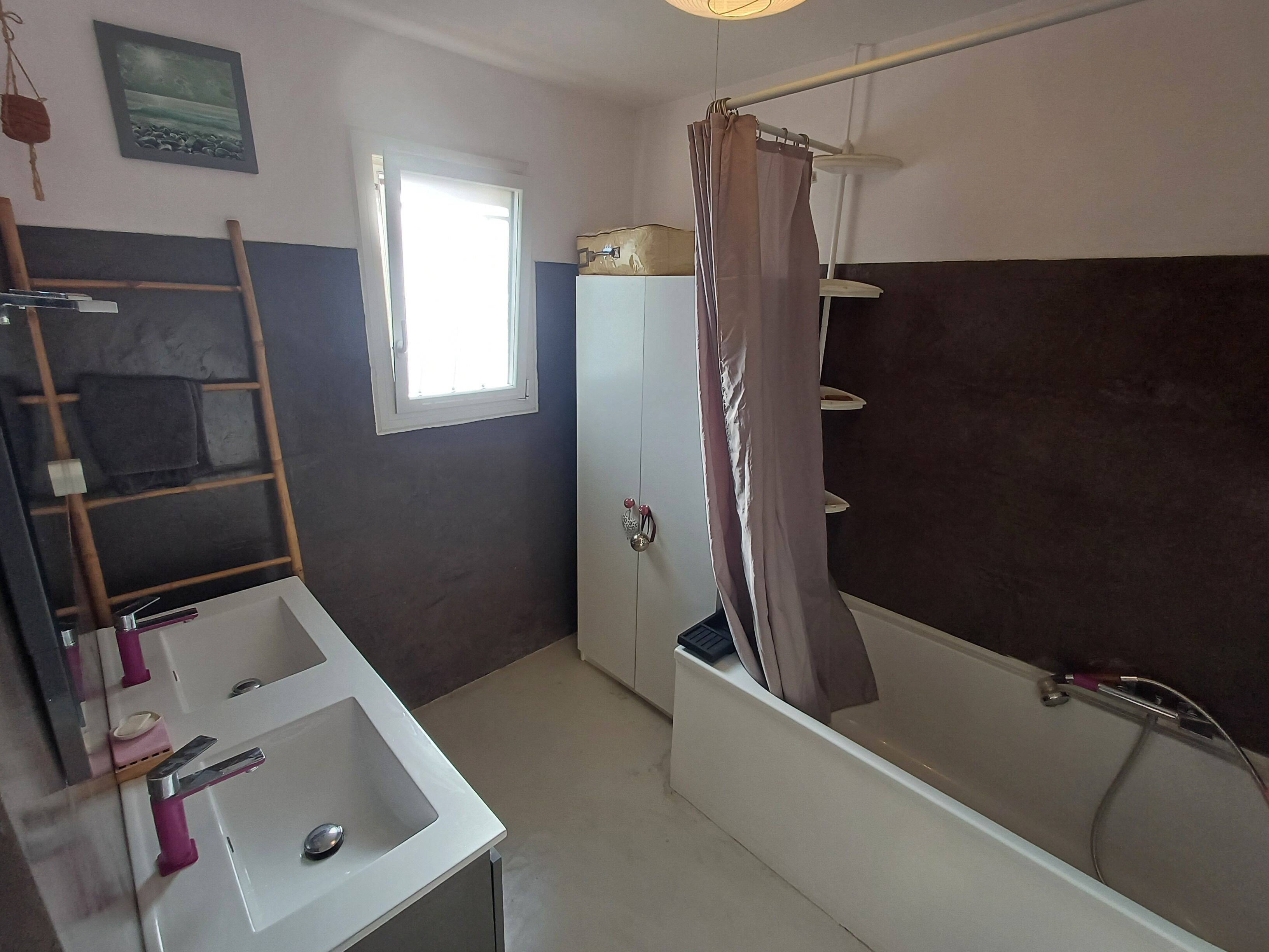 Une salle de bain avec une baignoire, un lavabo, un miroir, un porte-serviettes et une fenêtre.