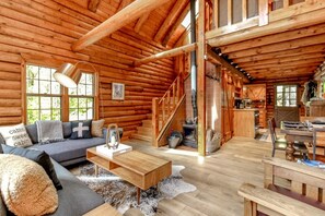 A log cabin interior with a sofa, coffee table, and a dining area. - 5 Miles to Rainier`s Nisqually Entrance – 8 Private Acres + Hot Tub (Ashford)