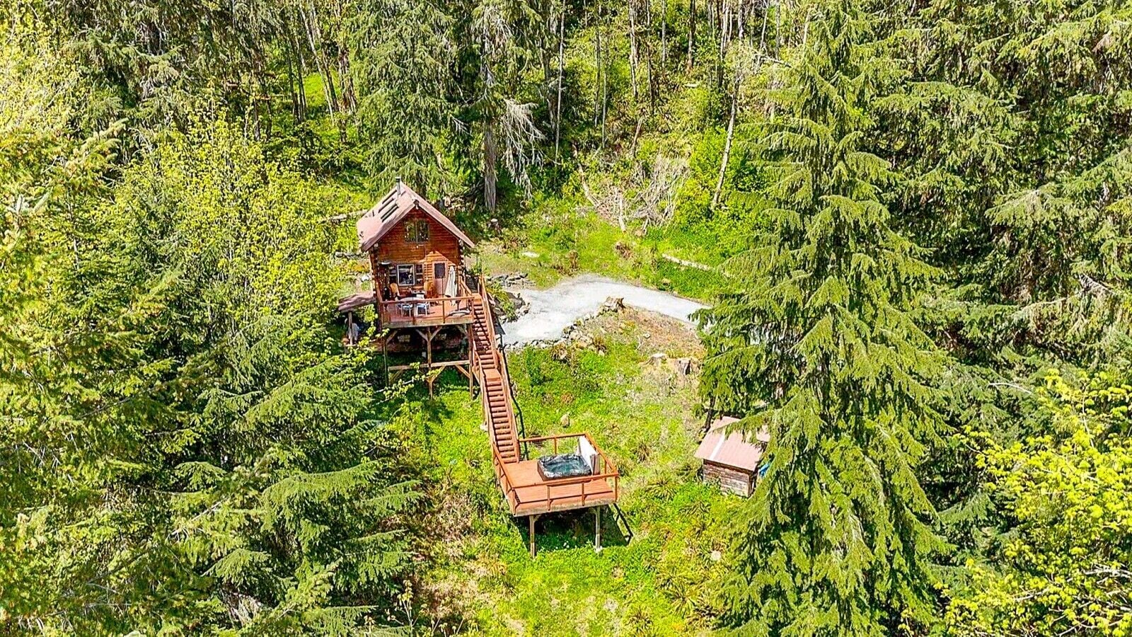 Una cabaña de madera con un balcón, rodeada de un bosque denso.