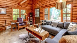 Ein Holzblockhaus-Innenraum mit einer Couch, einem Couchtisch und einer Gitarre.