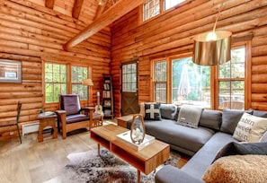 L'intérieur d'une cabane en rondins, avec un canapé, une table basse et une guitare.