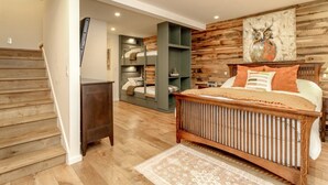 A bedroom with a bunk bed, a wooden headboard, a bedside table, and a wall-mounted shelf.