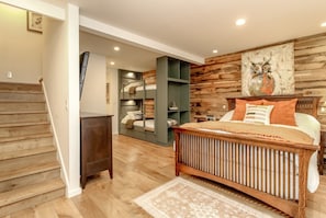 A bedroom with a bunk bed, a wooden headboard, a bedside table, and a wall-mounted shelf.