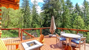 A wooden deck with outdoor furniture, including a table and chairs, surrounded by a railing.