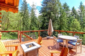 A wooden deck with outdoor furniture, including a table and chairs, surrounded by a railing.