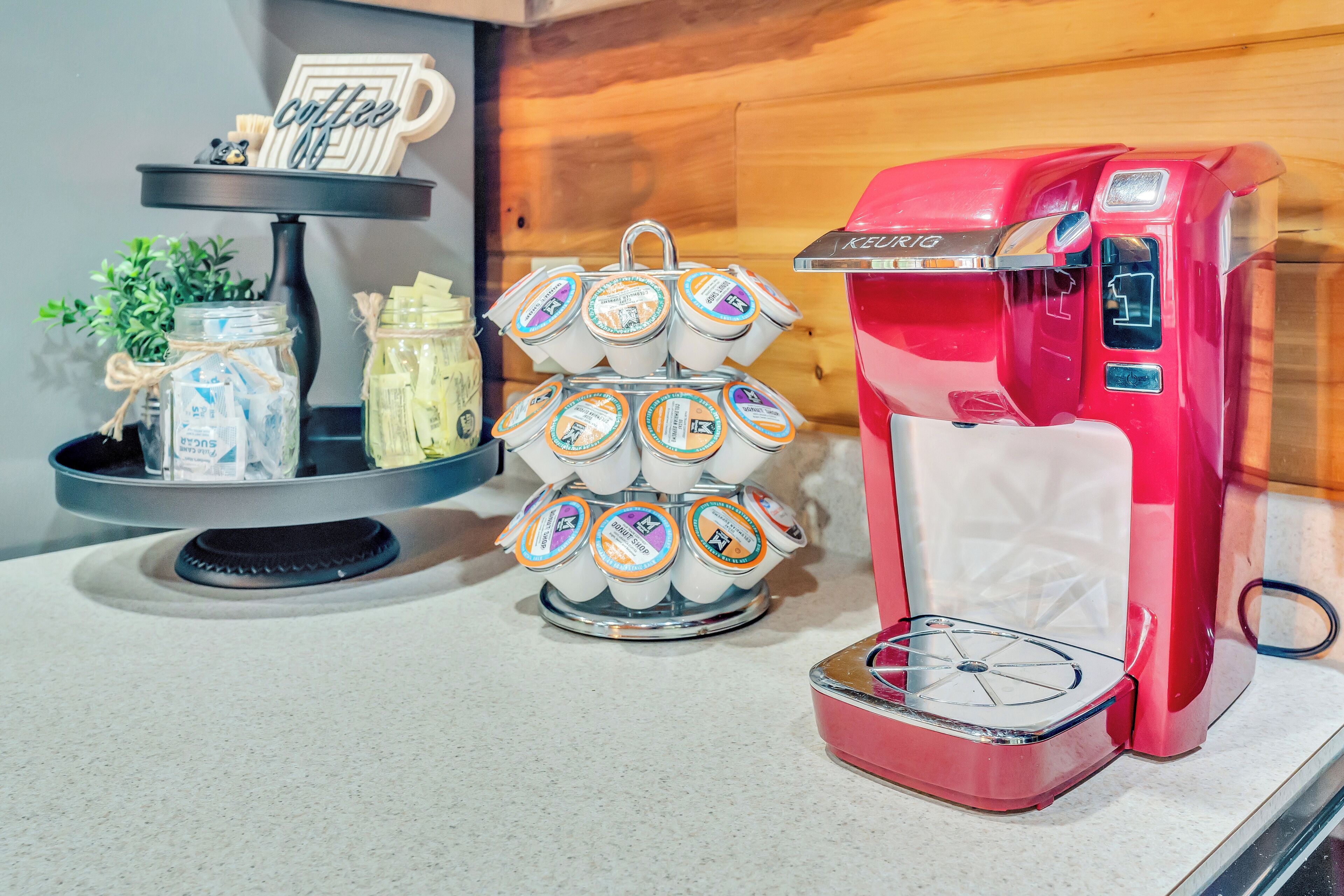 A coffee machine, a tray of coffee pods, and a jar of sugar on a countertop.