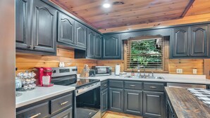 Una cocina moderna con armarios oscuros, electrodomésticos de acero inoxidable y techo de madera.
