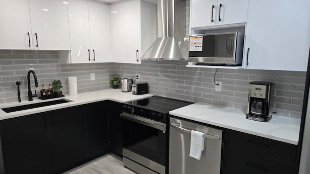 A modern kitchen with a stainless steel range hood, a microwave, and a coffee maker.