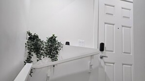 A staircase with a white handrail, a potted plant, and a white door with a doorbell.
