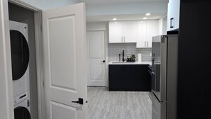 A modern kitchen with white cabinets, a black refrigerator, and a built-in island.