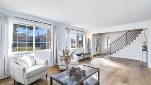 Un salon spacieux comprenant un canapé, une table basse et un escalier menant à un autre niveau.